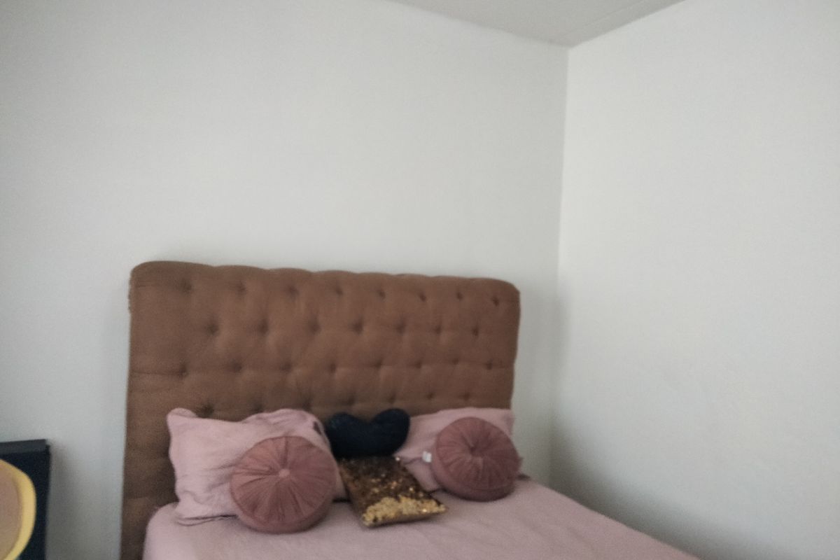 A simple bedroom space featuring plain white walls and neutral flooring.