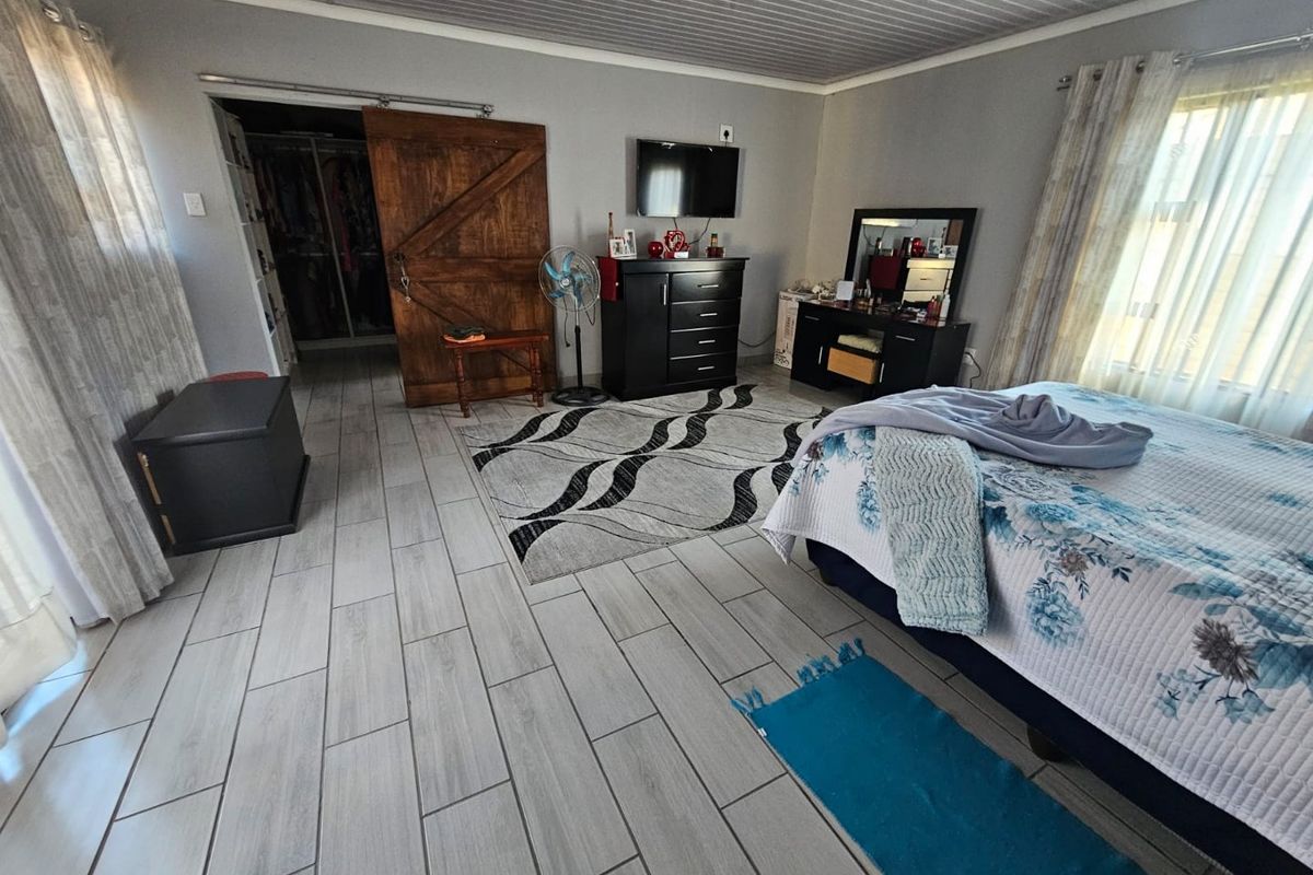 Spacious bedroom featuring wood-look tile flooring, a sliding barn-style door leading to a walk-in closet, and large windows providing natural light.