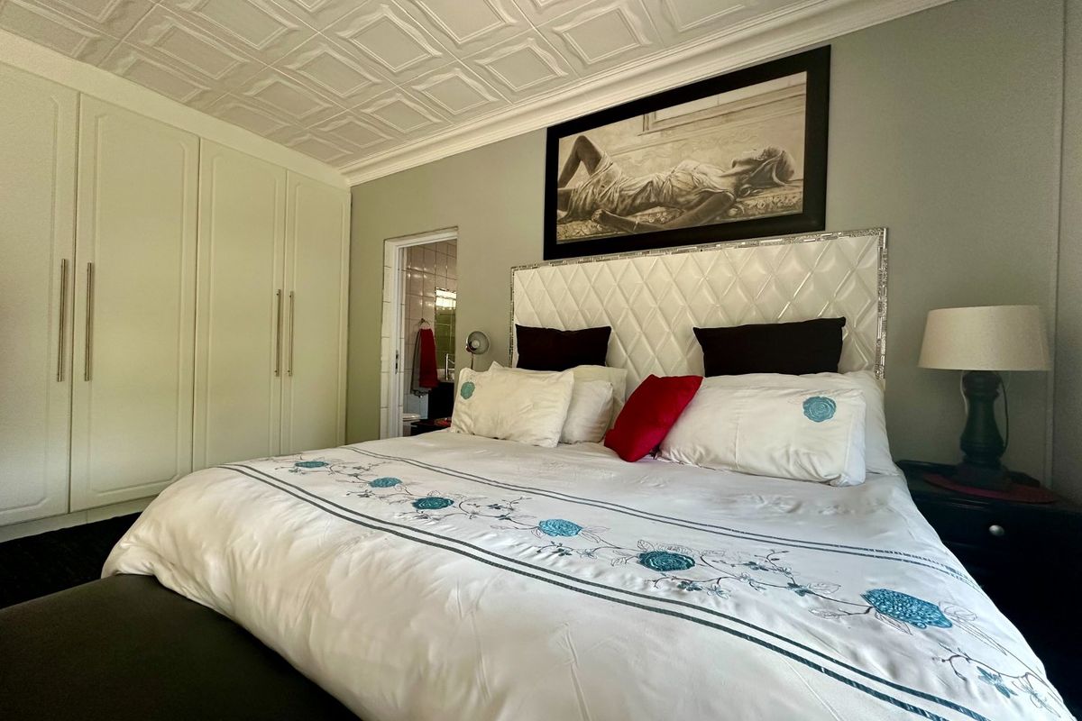 A well-maintained bedroom featuring built-in cupboards, a decorative coffered ceiling, and direct access to an en-suite bathroom.