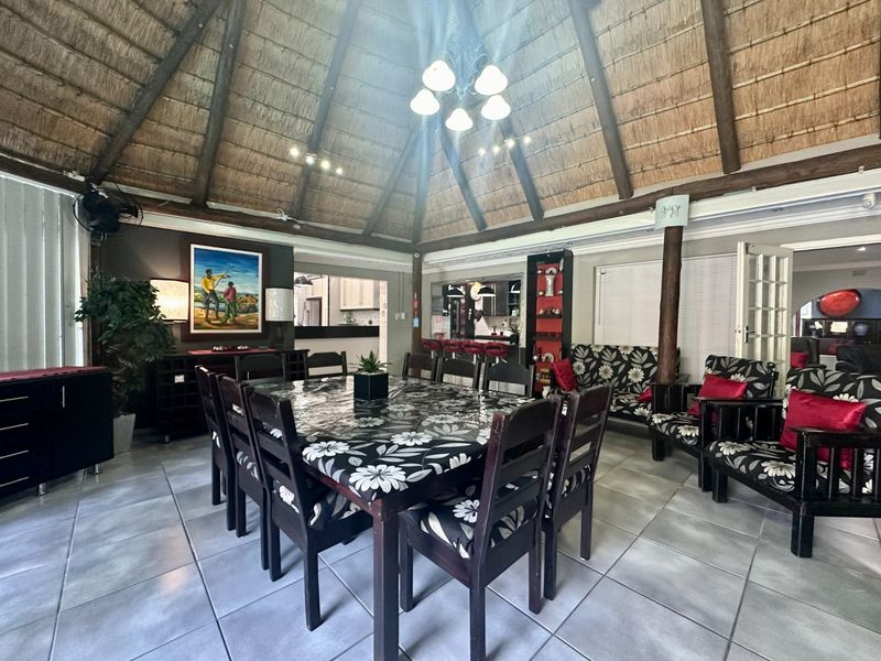 Spacious dining area featuring a high thatched roof with exposed timber beams and neutral ceramic floor tiles, offering a unique rustic aesthetic.
