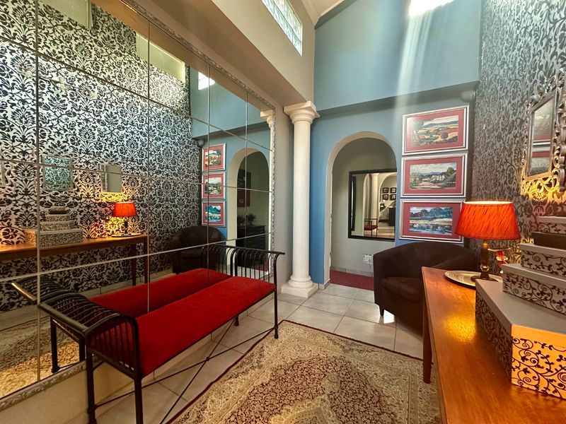 A grand entrance hall featuring a large mirrored wall, decorative archways, a classic column, and high ceilings with clerestory windows for natural light.
