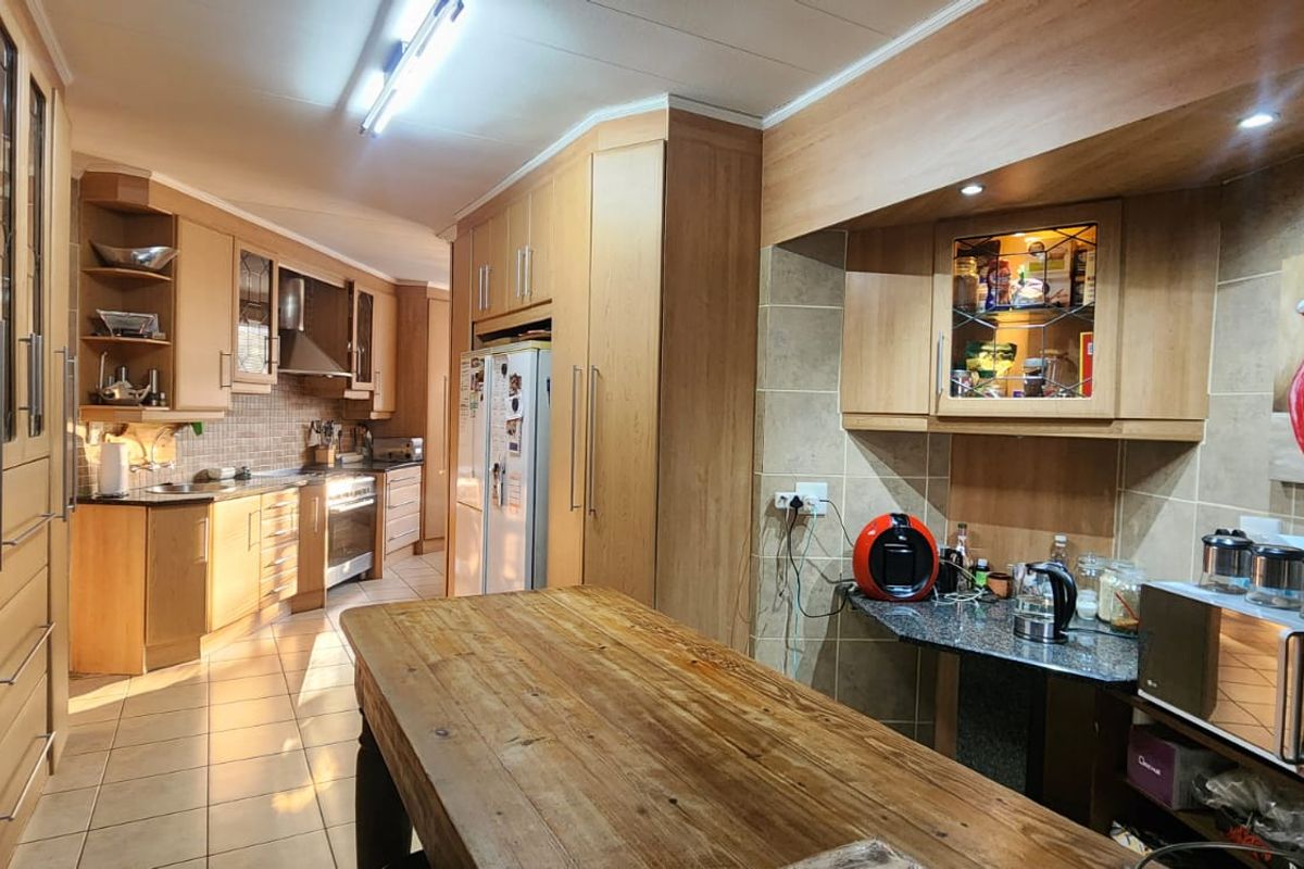 Spacious kitchen featuring extensive light wood cabinetry, tiled flooring, granite countertops, and a built-in oven with extractor fan.