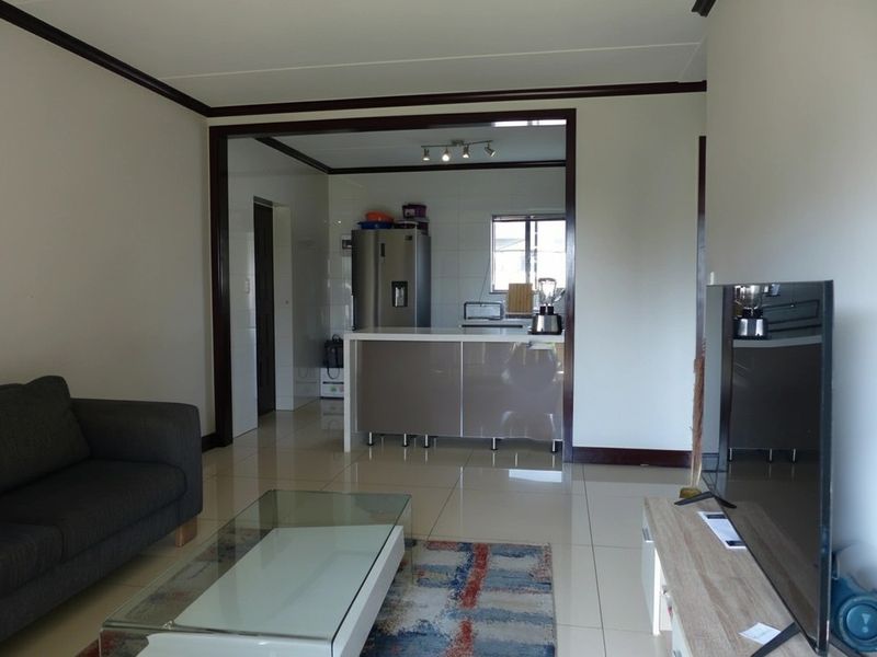 Open plan living area featuring tiled flooring and a kitchen with a central island and built-in cabinetry.
