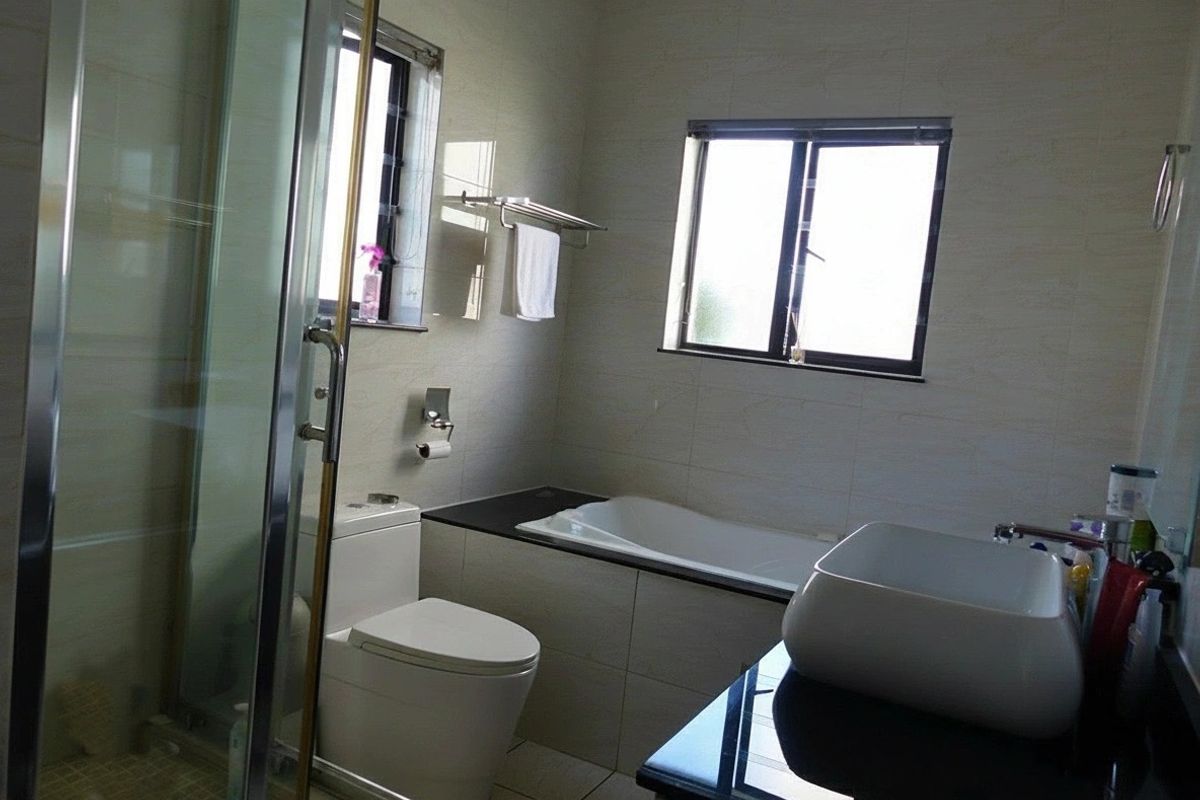 A well-appointed bathroom featuring a glass shower enclosure, a built-in bathtub, a modern vessel sink on a vanity, and neutral wall tiling.