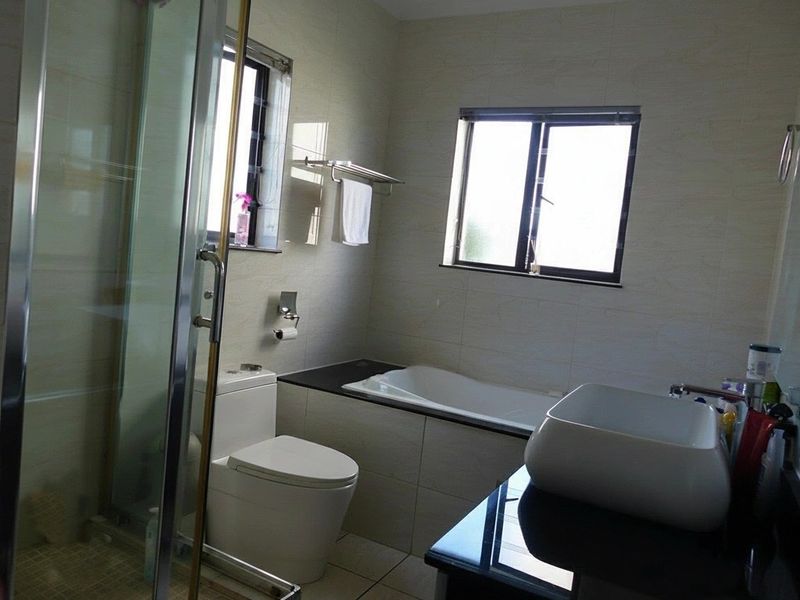 A well-appointed bathroom featuring a glass shower enclosure, a built-in bathtub, a modern vessel sink on a vanity, and neutral wall tiling.