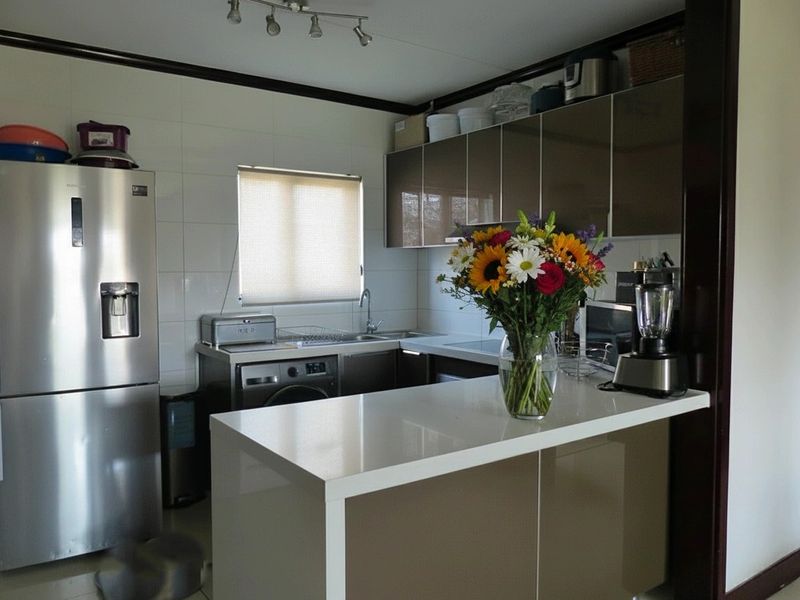 Modern kitchen featuring sleek cabinetry, stone countertops, a breakfast bar, and tiled splashbacks, offering a functional and contemporary cooking space.