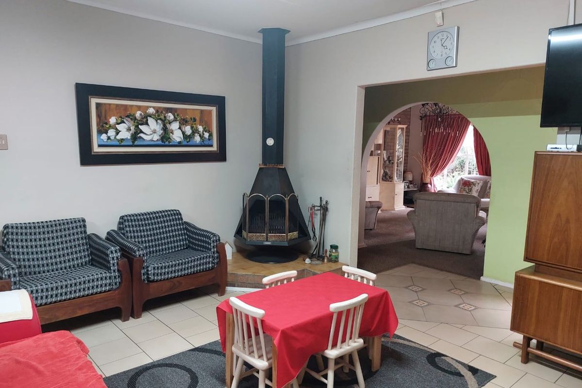 A living room featuring a central freestanding fireplace, tiled flooring, and an arched entryway leading to an adjacent living space.