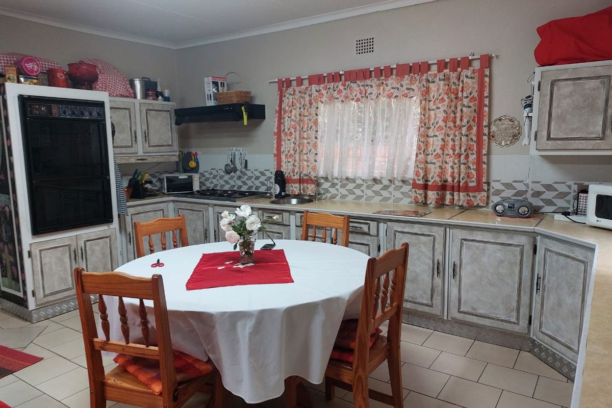 A functional kitchen featuring built-in cabinetry, a built-in oven, hob, extractor fan, and tiled flooring, offering a traditional layout with ample storage space.