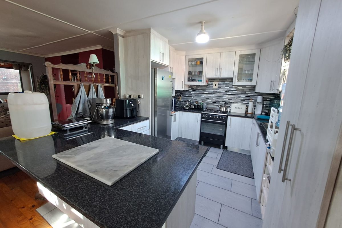 A functional kitchen featuring granite countertops, a central island, built-in cabinetry, and a gas stove with a tiled backsplash.