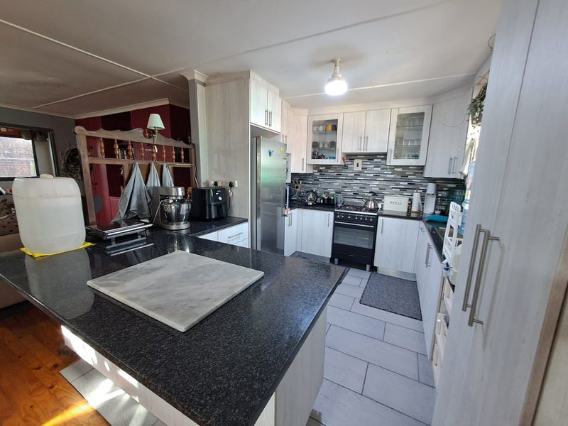 A functional kitchen featuring granite countertops, a central island, built-in cabinetry, and a gas stove with a tiled backsplash.