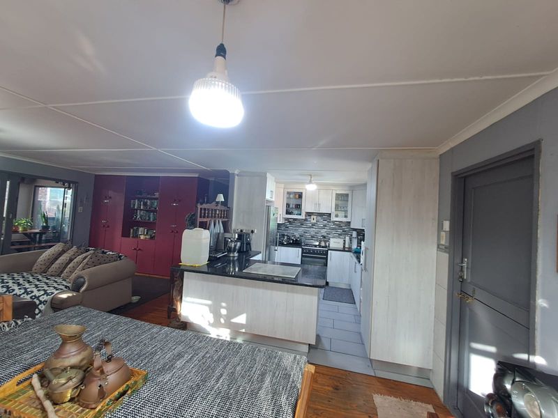 Open plan living area featuring a kitchen with granite countertops, built-in cabinetry, and a mix of tiled and wooden flooring.