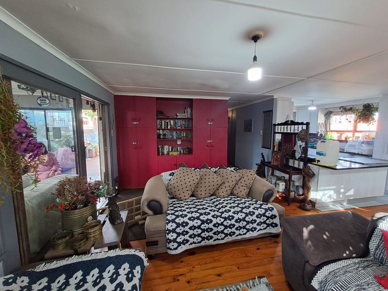 Open plan living area featuring hardwood floors, built-in red cabinetry, and sliding doors leading to an outdoor patio space.