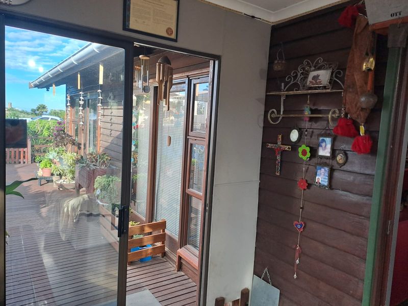 A covered patio area featuring timber decking and wall cladding, accessible through a sliding glass door, providing a rustic outdoor living space.