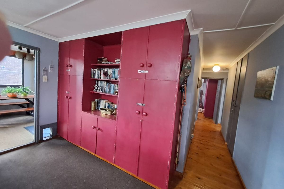Living area featuring extensive built-in red cabinetry, hardwood flooring, and access to an adjacent patio area.