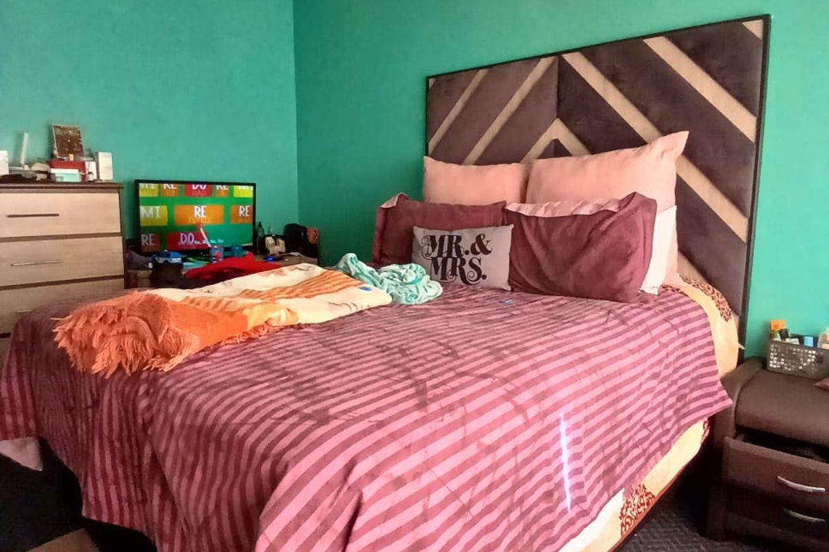 A bedroom featuring teal painted walls and carpeted flooring, providing a functional sleeping space with potential for cosmetic updates.