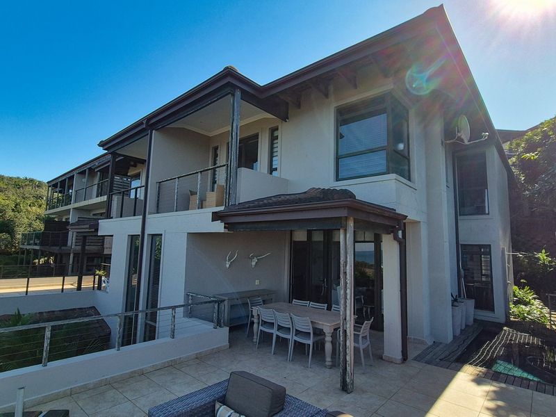 Rear view of a multi-level townhouse featuring a tiled patio, covered veranda, balcony, and established exterior finishes.