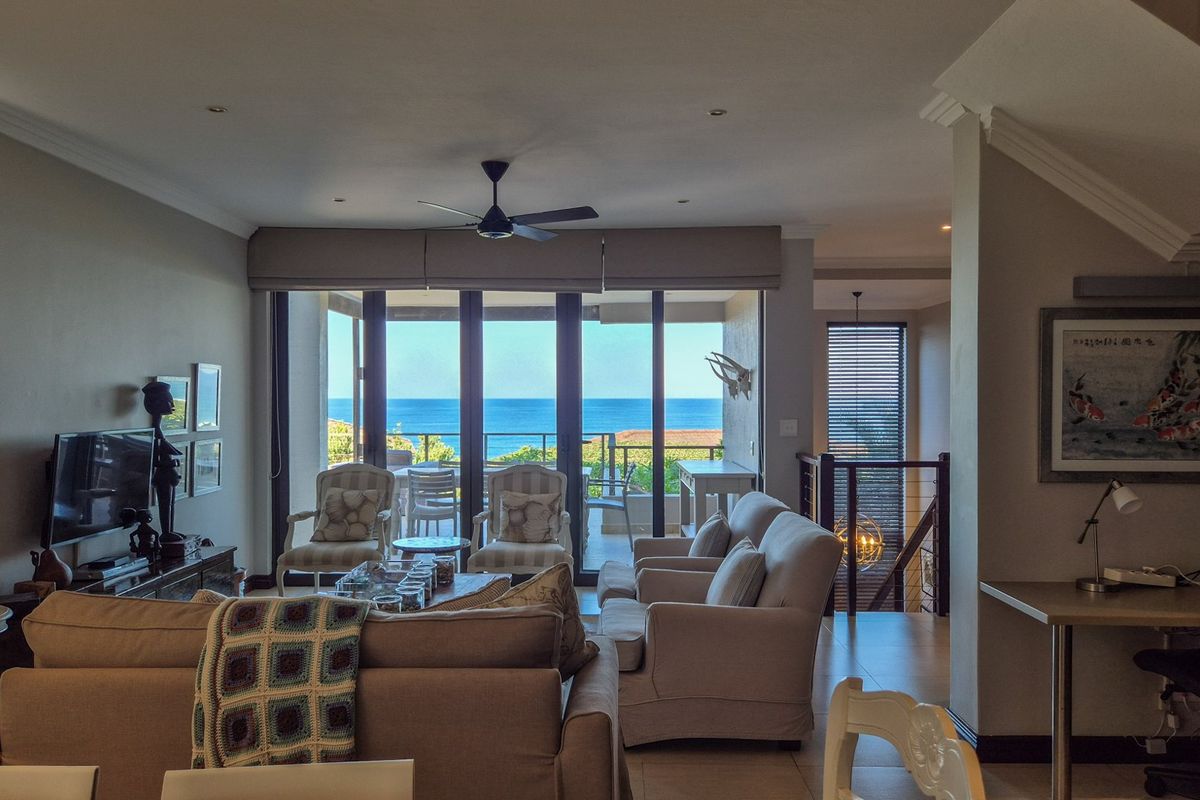 Spacious open-plan living area featuring recessed lighting, crown molding, and large sliding glass doors that open to a balcony with ocean views.