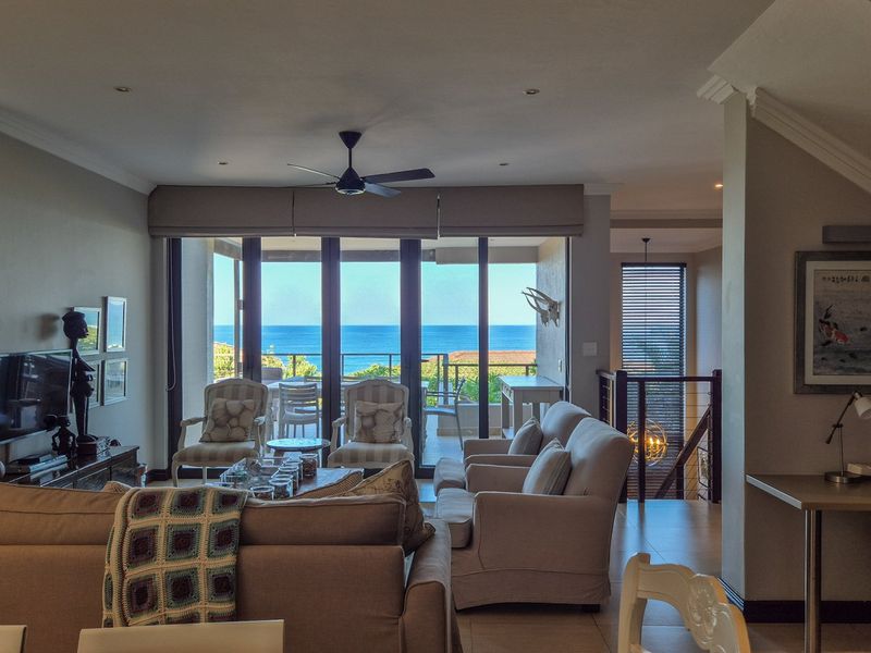 Spacious open-plan living area featuring recessed lighting, crown molding, and large sliding glass doors that open to a balcony with ocean views.