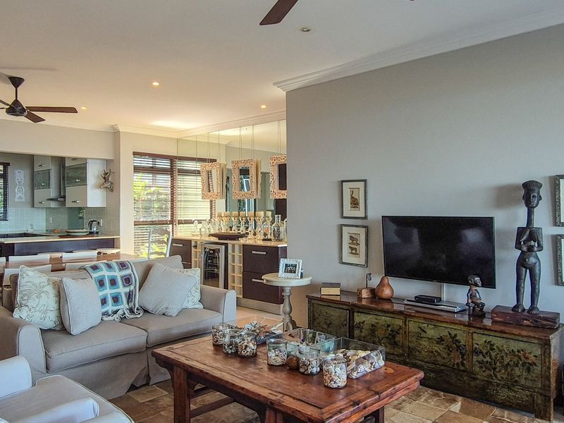 Spacious open-plan living area featuring a modern kitchen with built-in cabinetry, wine cooler, and tiled flooring, seamlessly flowing into the lounge space.