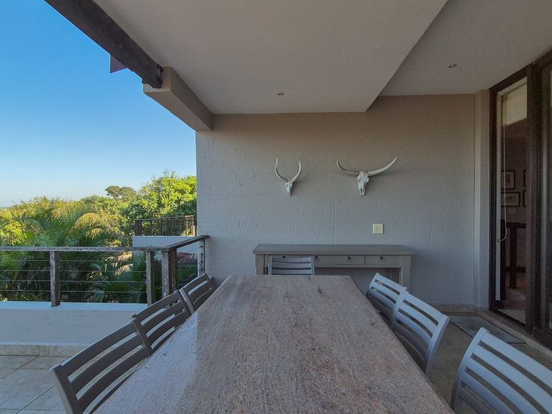 A spacious covered patio featuring tiled flooring, recessed lighting, and a railing, offering an ideal outdoor space for dining and relaxation.