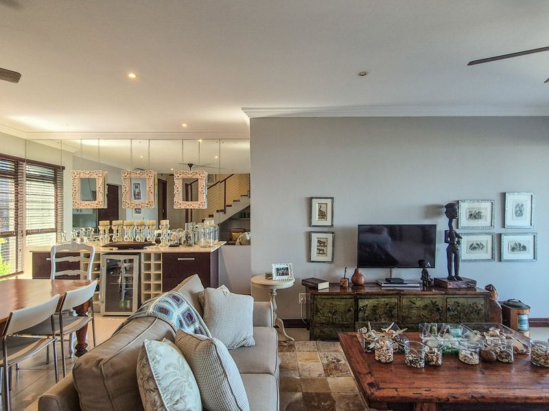 Spacious open-plan living and dining area featuring tiled floors, ceiling fans, recessed lighting, and a mirrored wall with integrated cabinetry and wine storage.