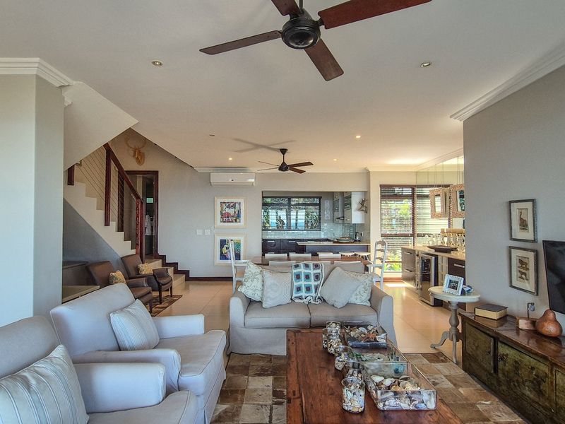 Spacious open-plan living and dining area featuring tiled floors, recessed lighting, ceiling fans, and a modern kitchen with integrated cabinetry and island.