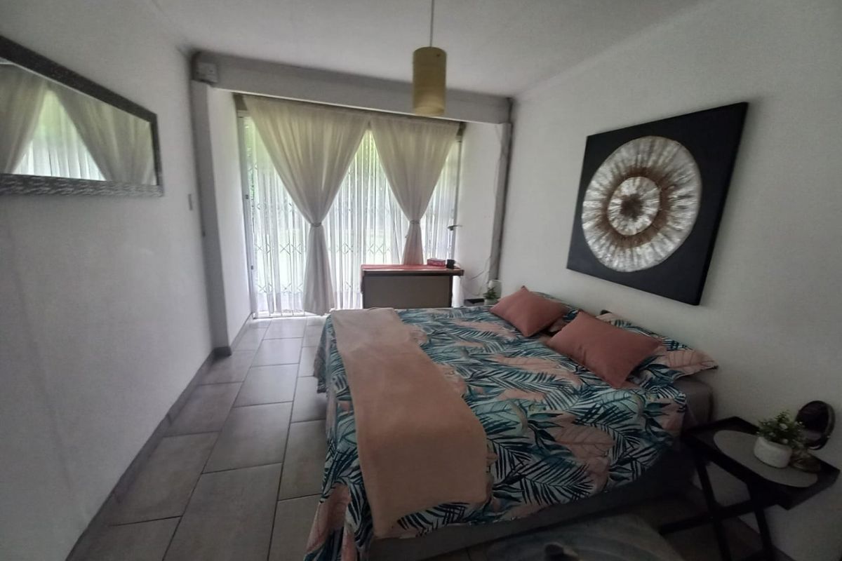 A bedroom featuring tiled flooring and a sliding door with security gate, providing access to the exterior.