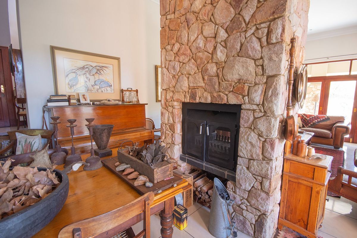 A living area featuring a prominent floor-to-ceiling natural stone fireplace with a built-in wood-burning stove and tiled flooring.