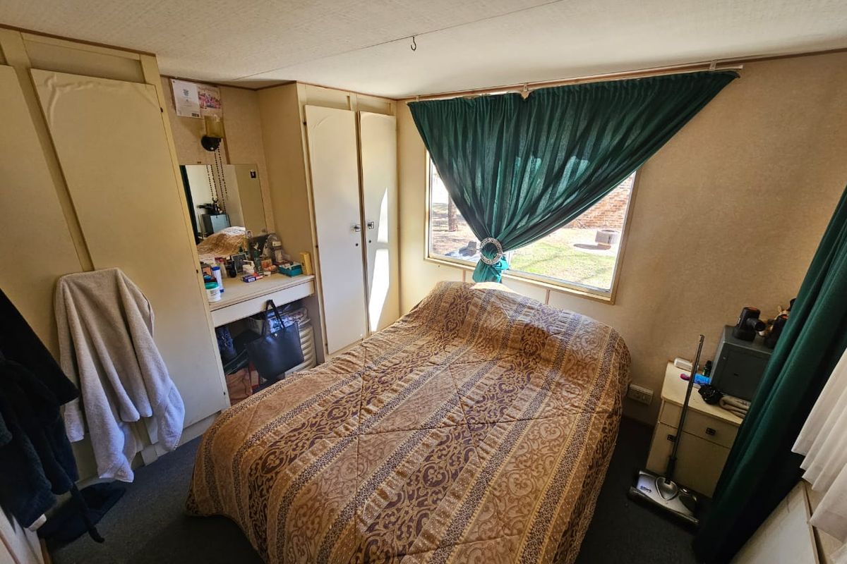 A compact bedroom featuring built-in wardrobes, a vanity area, and a window with natural light.