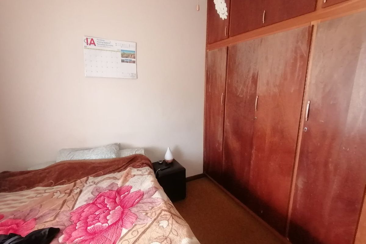 A bedroom featuring a large, dated built-in wooden wardrobe with overhead storage compartments.