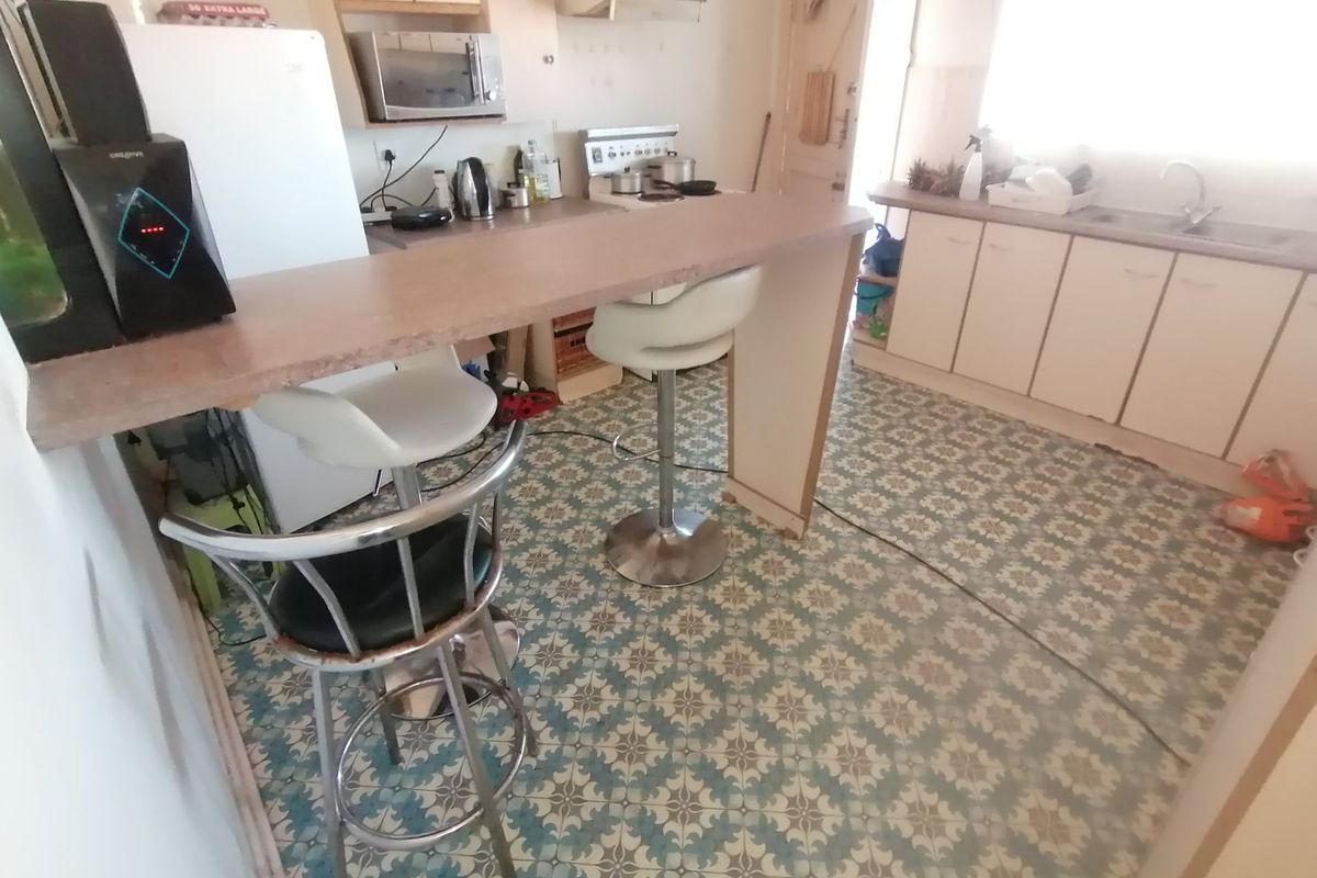 A dated kitchen featuring a breakfast bar, built-in cabinetry, and patterned floor tiles, offering a functional layout with potential for modernization.