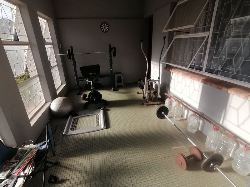 A functional home gym space featuring tiled flooring and large windows providing natural light, suitable for fitness equipment and exercise activities.