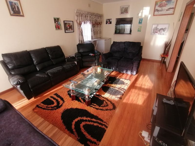 A living room featuring polished wooden flooring and a window with curtain rails.