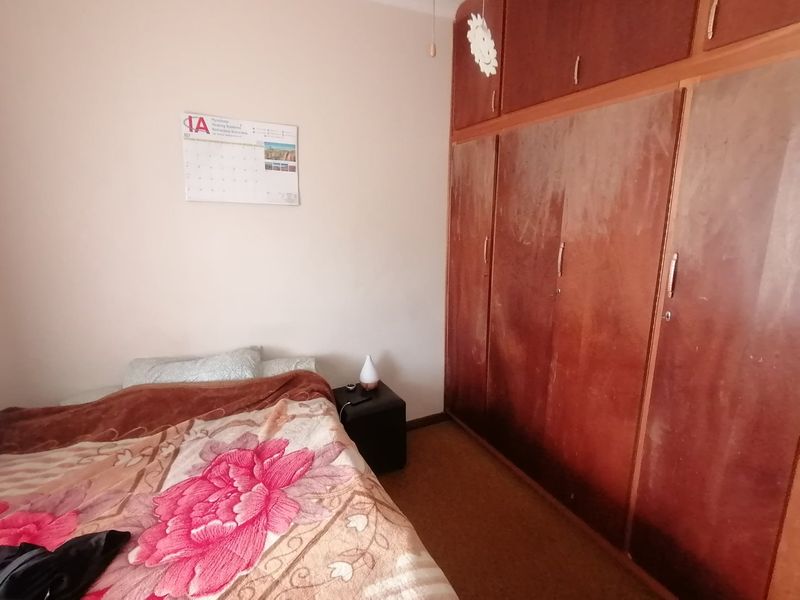A bedroom featuring a large, dated built-in wooden wardrobe with overhead storage compartments.