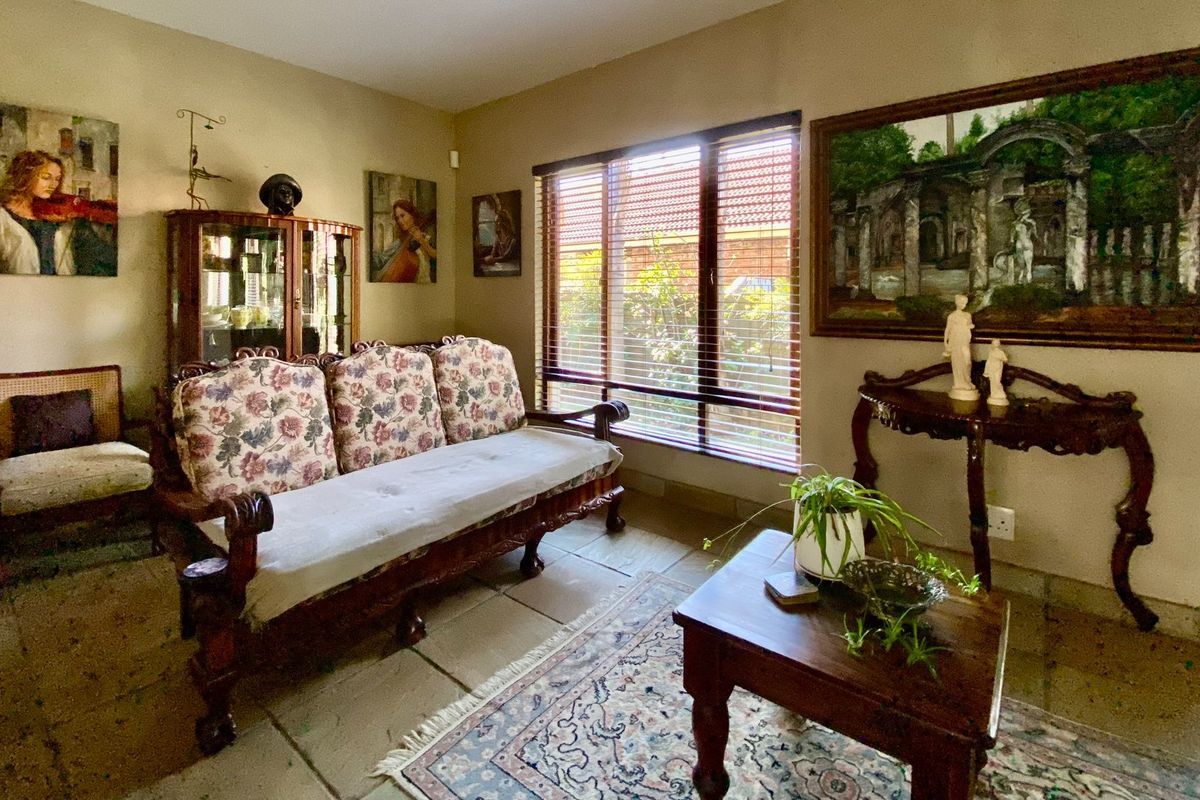 A cozy living room featuring tiled flooring and large windows with venetian blinds, offering a comfortable and traditional living space.