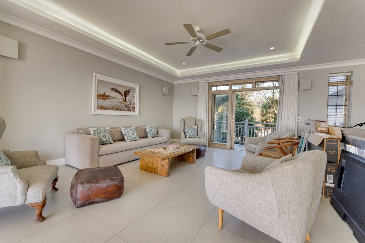 Spacious living room featuring a tray ceiling with recessed lighting, ceiling fan, and large sliding glass doors leading to an outdoor balcony.