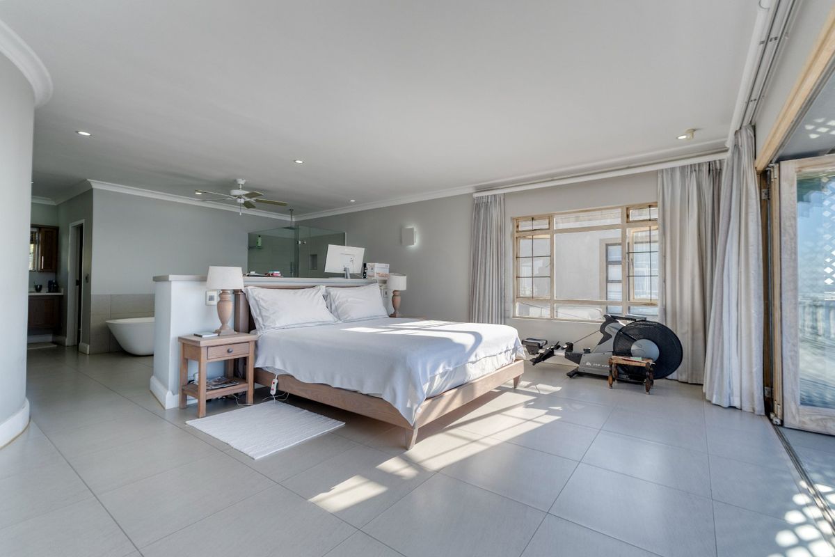 Spacious open-plan bedroom featuring a semi-partitioned en-suite bathroom with a freestanding bathtub and large windows providing ample natural light.