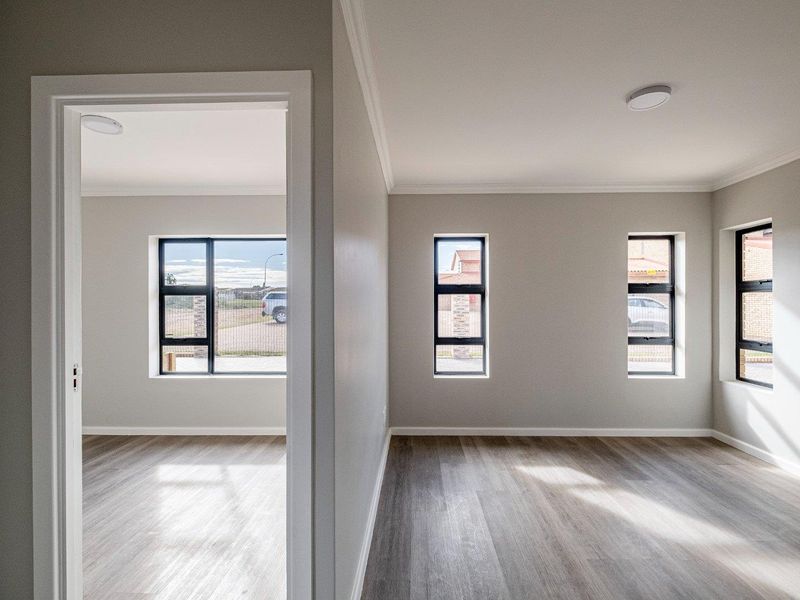 Bright and modern interior space featuring neutral walls, contemporary laminate flooring, and sleek black-framed windows providing ample natural light.