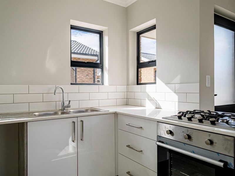 Modern kitchen featuring white cabinetry, stone countertops, subway tile backsplash, stainless steel sink, and a built-in gas oven and cooktop.