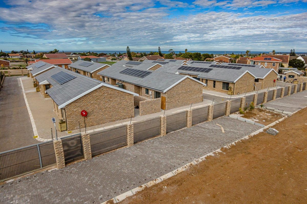 Aerial view of a modern townhouse complex featuring brick facades, tiled roofs with solar panels, and secure perimeter fencing with gated access.