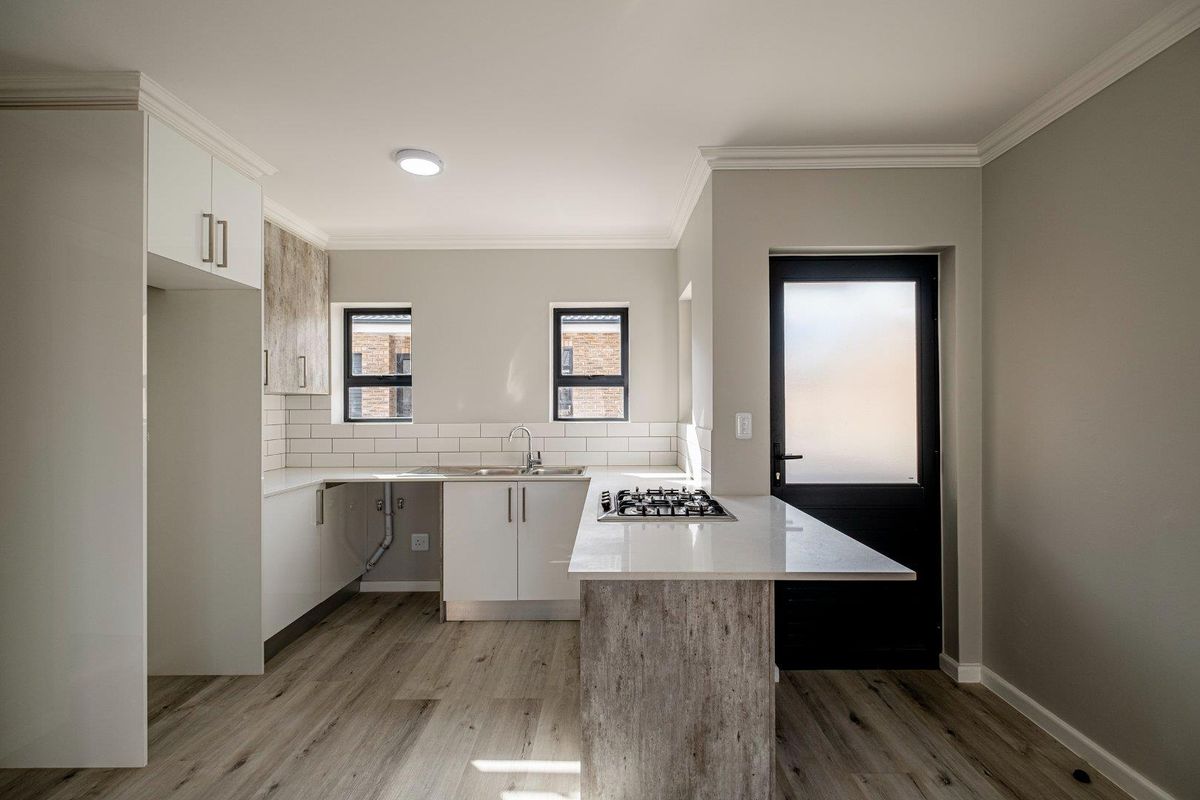 Modern kitchen featuring white cabinetry, stone countertops, a gas hob, subway tile backsplash, and wood-look laminate flooring with direct exterior access.