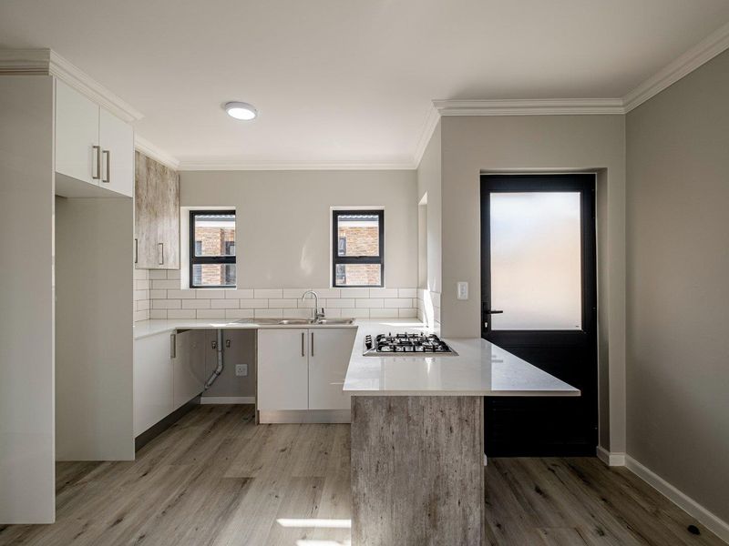 Modern kitchen featuring white cabinetry, stone countertops, a gas hob, subway tile backsplash, and wood-look laminate flooring with direct exterior access.