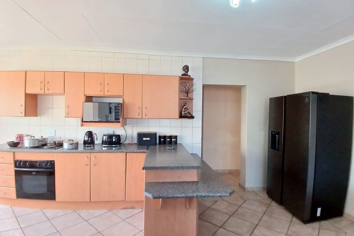 A functional kitchen featuring light wood-tone cabinetry, a breakfast bar, tiled flooring, and a built-in oven with a hob.
