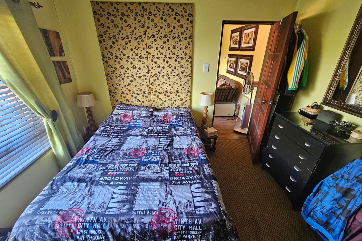 A bedroom featuring carpeted flooring, a built-in wardrobe with patterned doors, and a doorway leading to an adjacent living area.