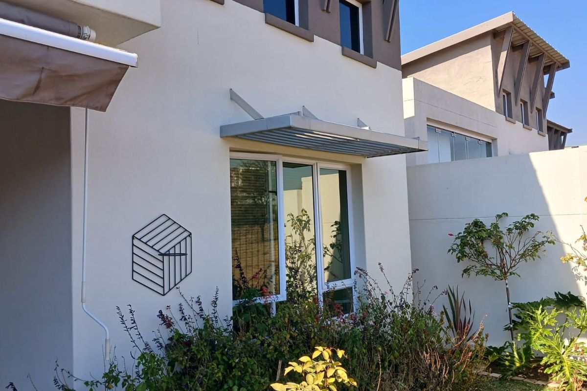 A well-maintained exterior rear view of the retirement village unit, featuring a modern metal window awning and clean architectural lines.