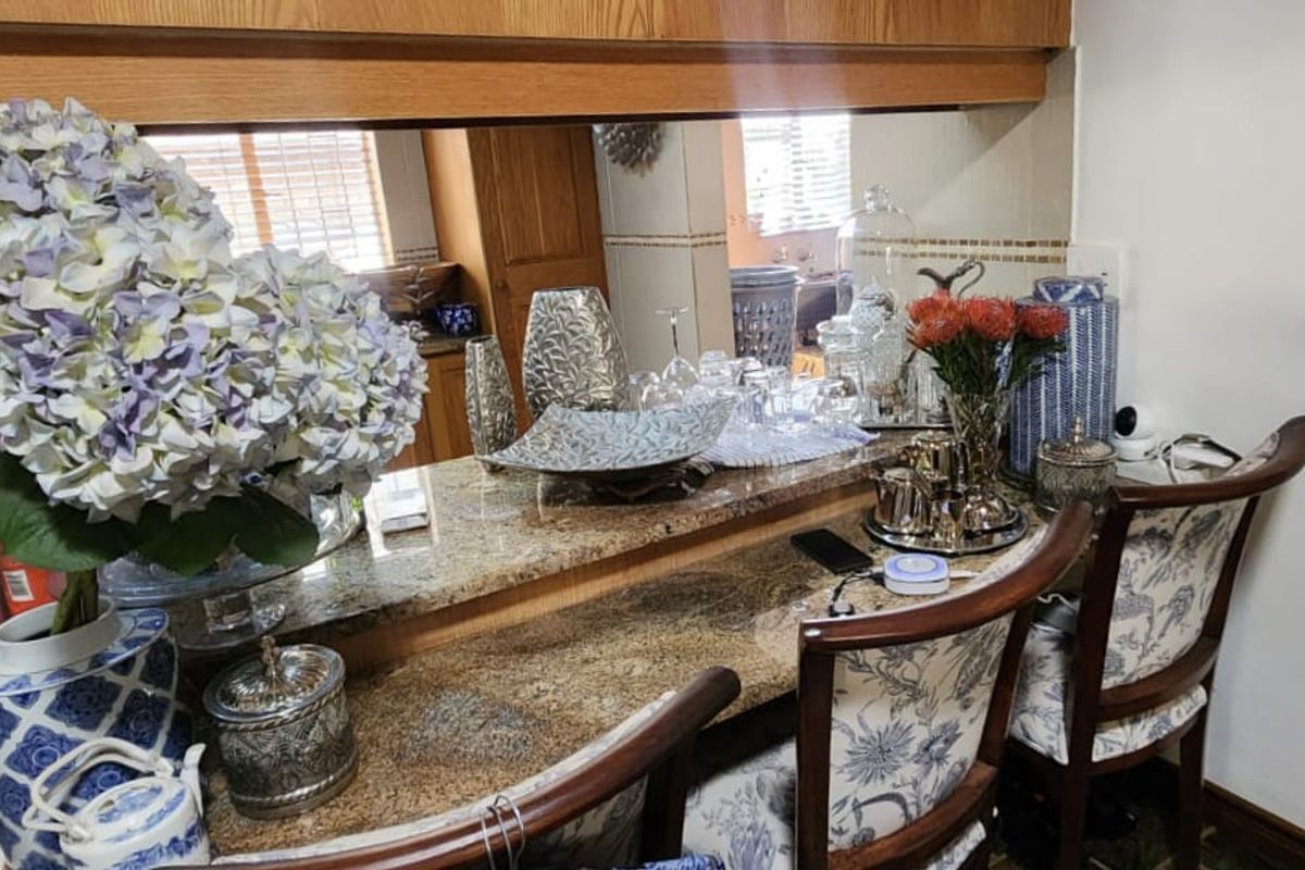 A kitchen breakfast bar featuring granite countertops and a mirrored backsplash, providing a functional transition space between the kitchen and living area.