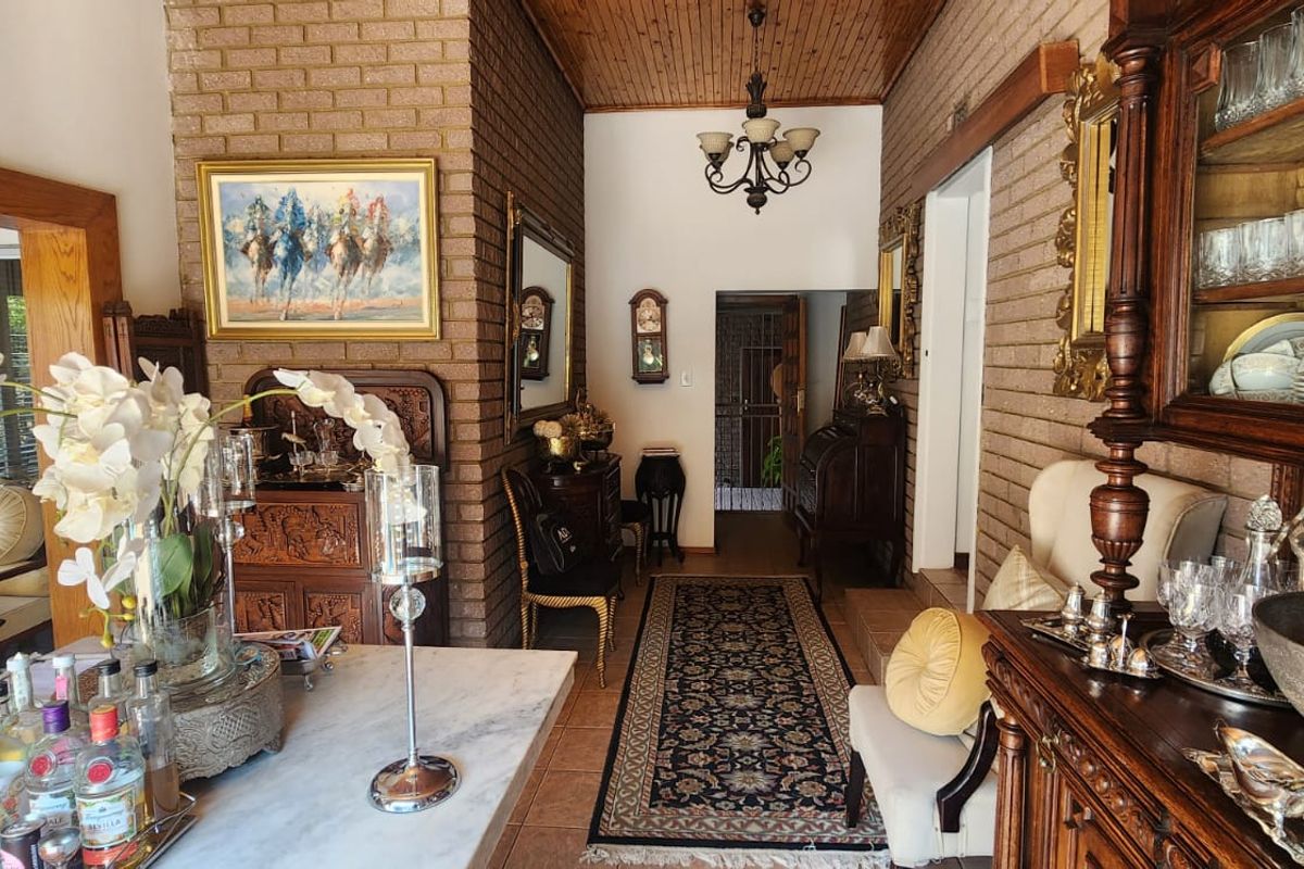 A living area featuring exposed brick walls, a timber-paneled ceiling, and a classic chandelier, creating a traditional and warm atmosphere.