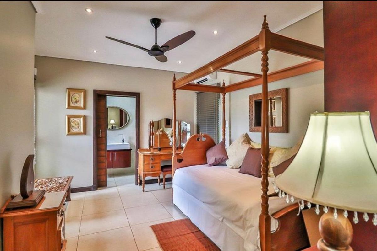 Spacious bedroom featuring tiled flooring, a ceiling fan, and an en-suite bathroom with a modern vanity.