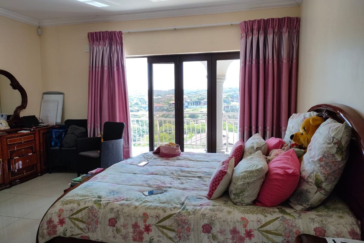 Spacious bedroom featuring tiled flooring and large sliding glass doors that open onto a balcony with scenic views.