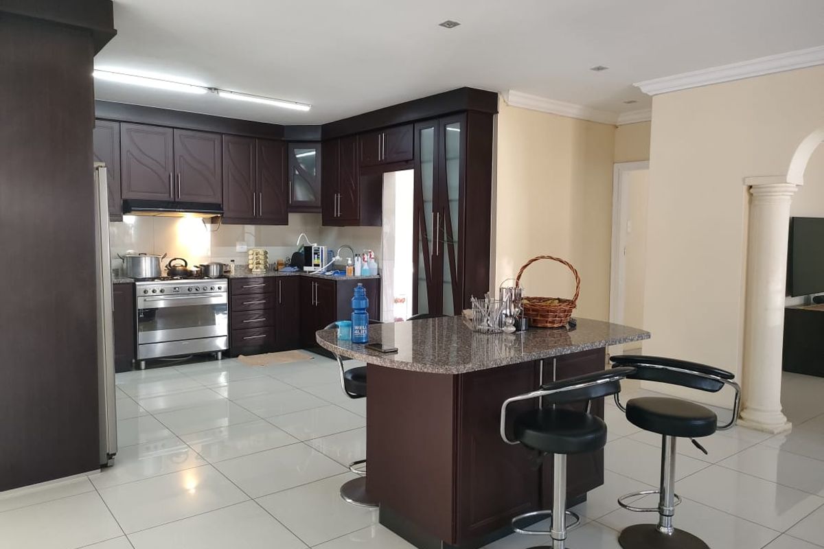 Spacious kitchen featuring dark wood cabinetry, granite countertops, a central island, and tiled flooring, offering a functional and well-maintained cooking and dining space.